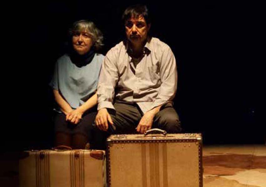 Una dona i un home asseguts davant d'unes maletes